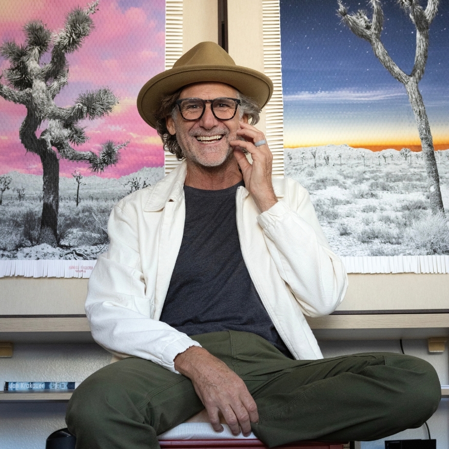 Marcelo Bengoechea seated in front of woven photographic works