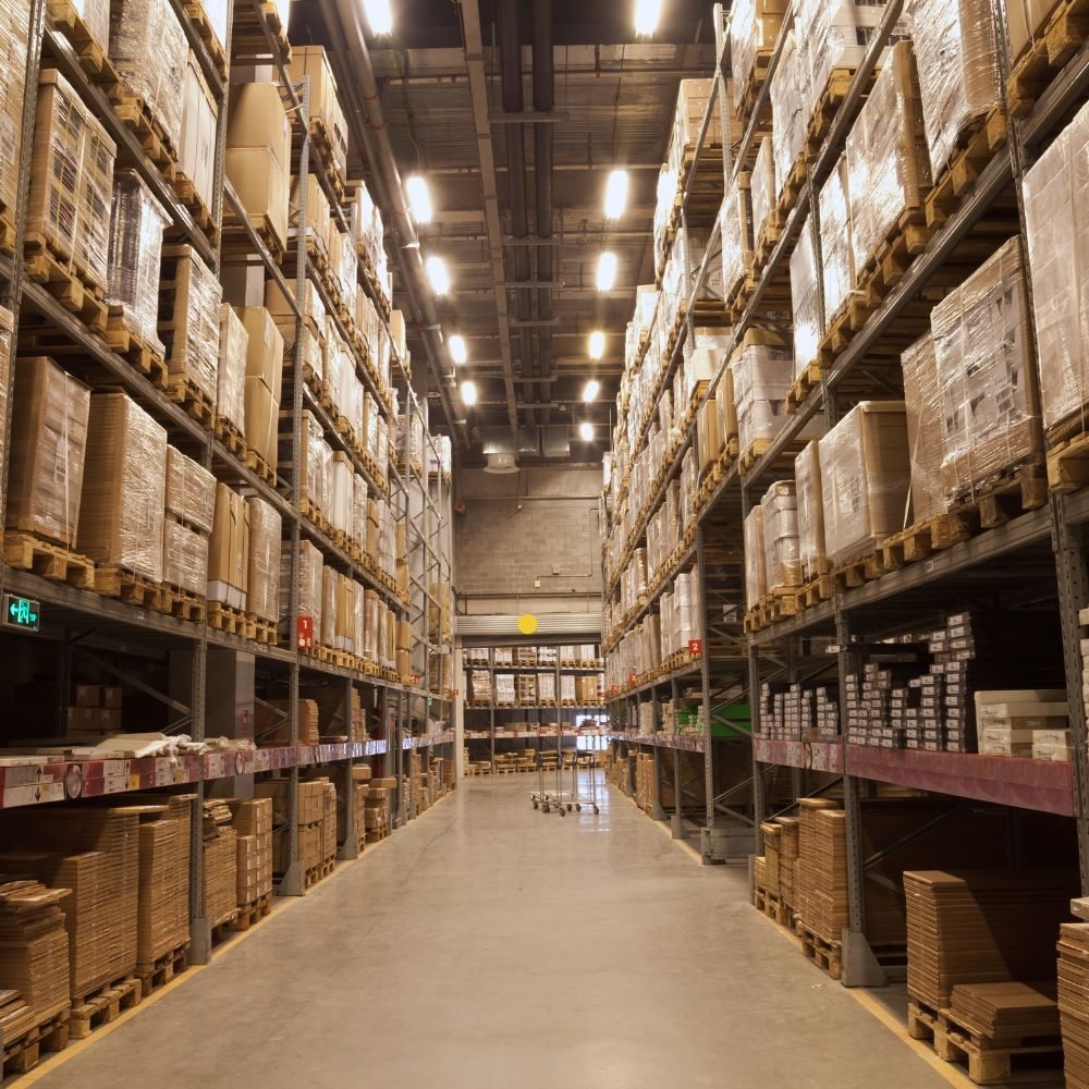 Tall warehouse racks filled with boxed merchandise along a central aisle