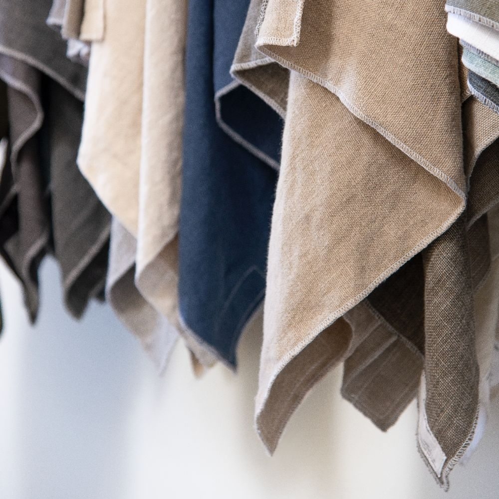 Overlapping upholstery swatches in cream, stone, taupe, and deep blue